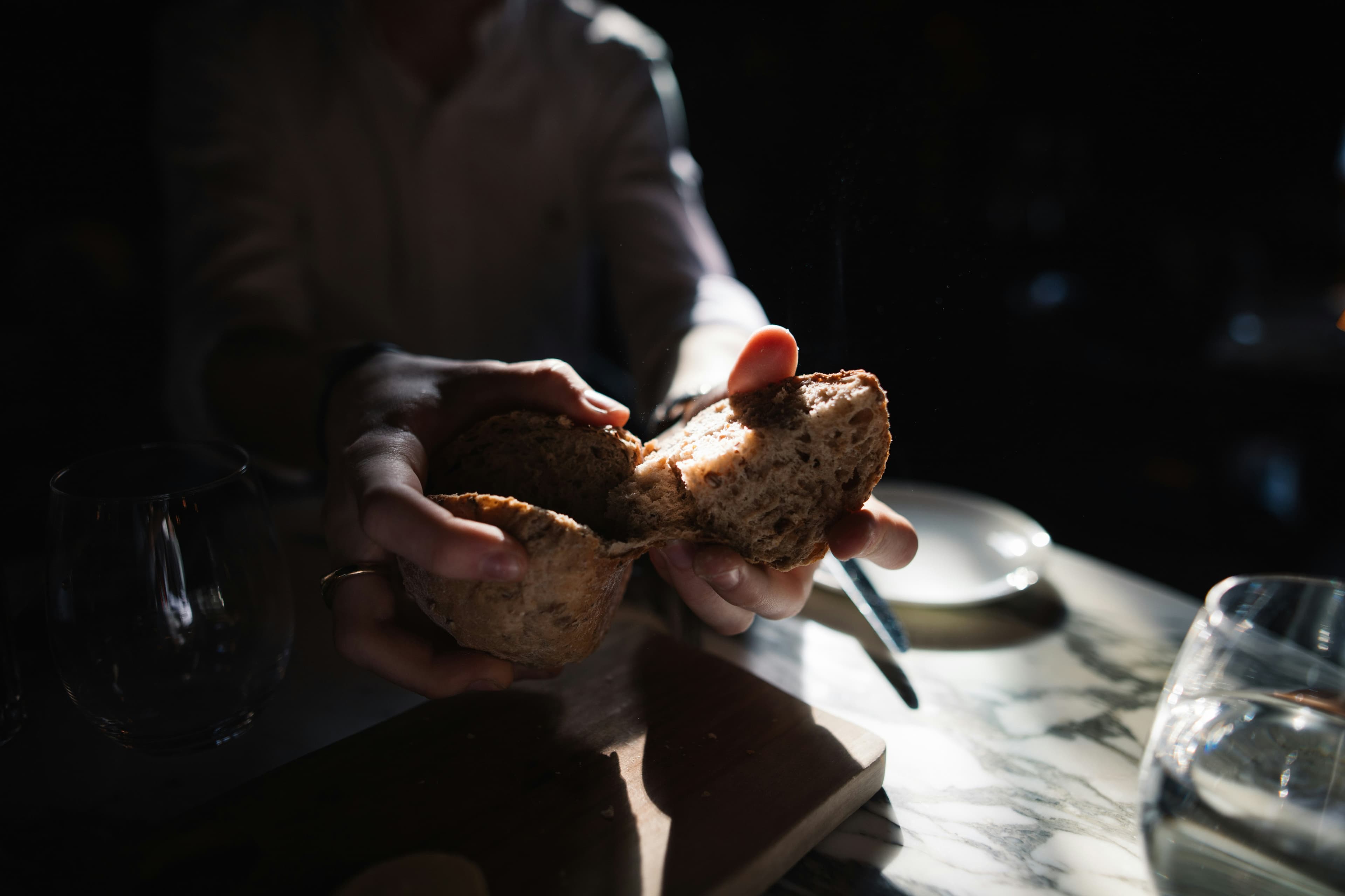 Hands tearing a loaf of bread.