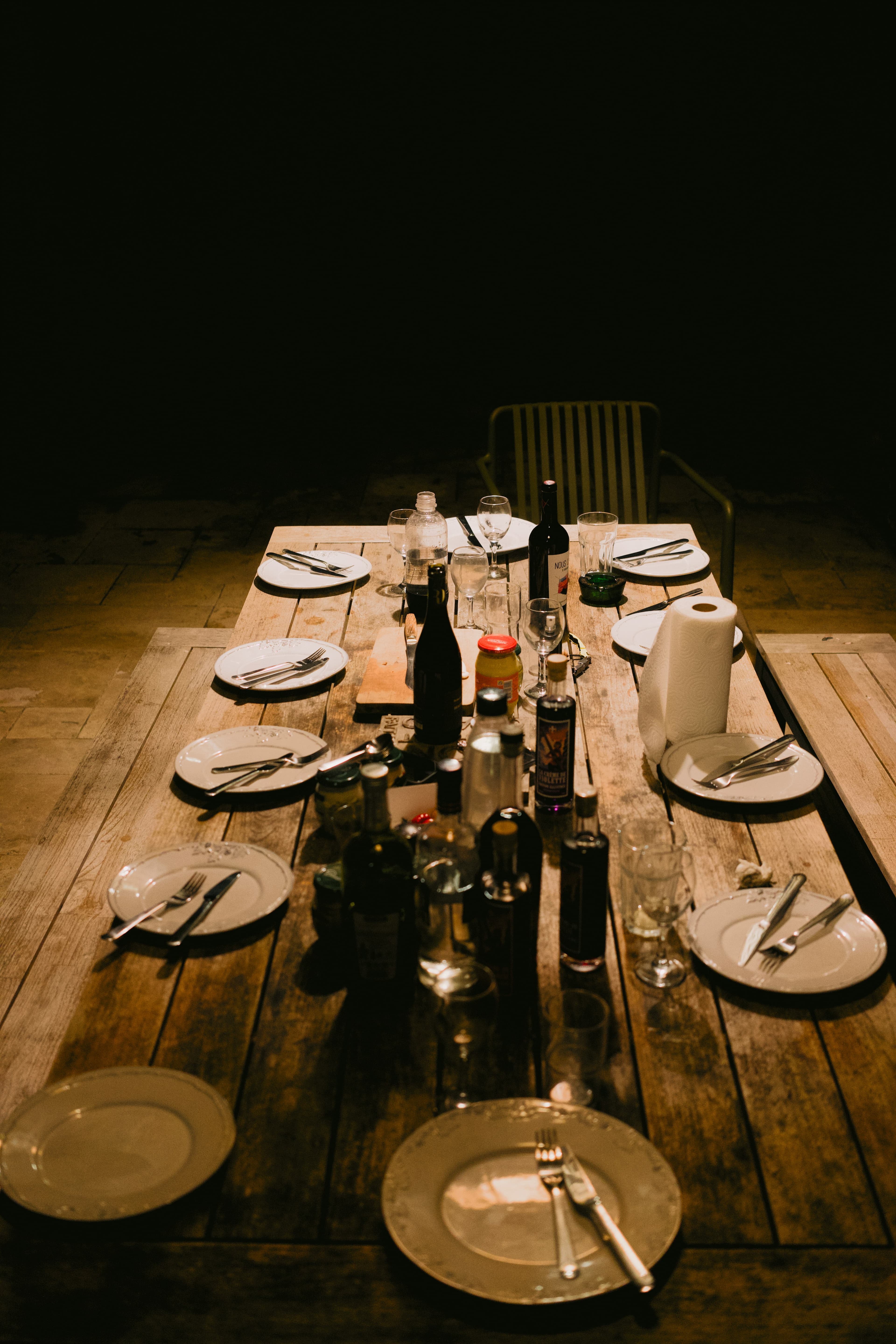 A long table set with plates, glasses, and lit candles before guests arrive.